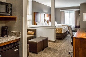 A hotel room with a kitchenette, a bed with a headboard, a desk, and a view of the outdoors. - Comfort Suites Hartville - North Canton (Hartville)