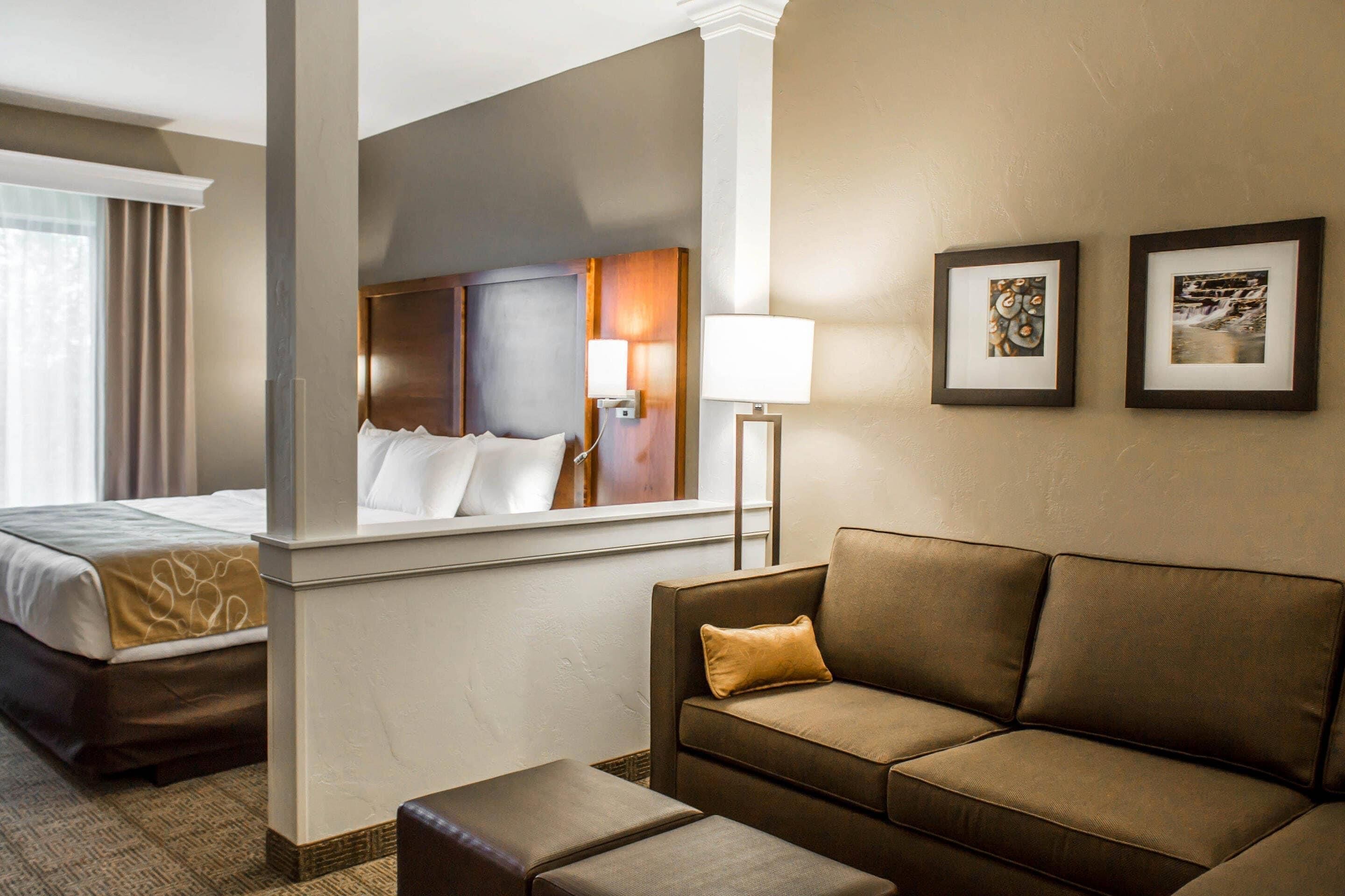 Una habitación de hotel con cama, sofá, una mesa de centro y dos cuadros en la pared.