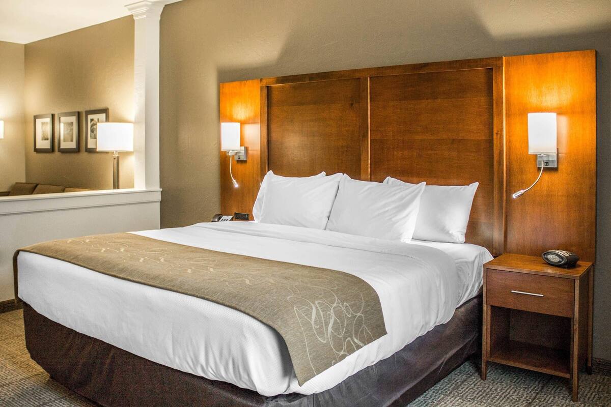 Een hotelkamer met een groot bed, bedlampen, een nachtkastje en een telefoon aan de muur.