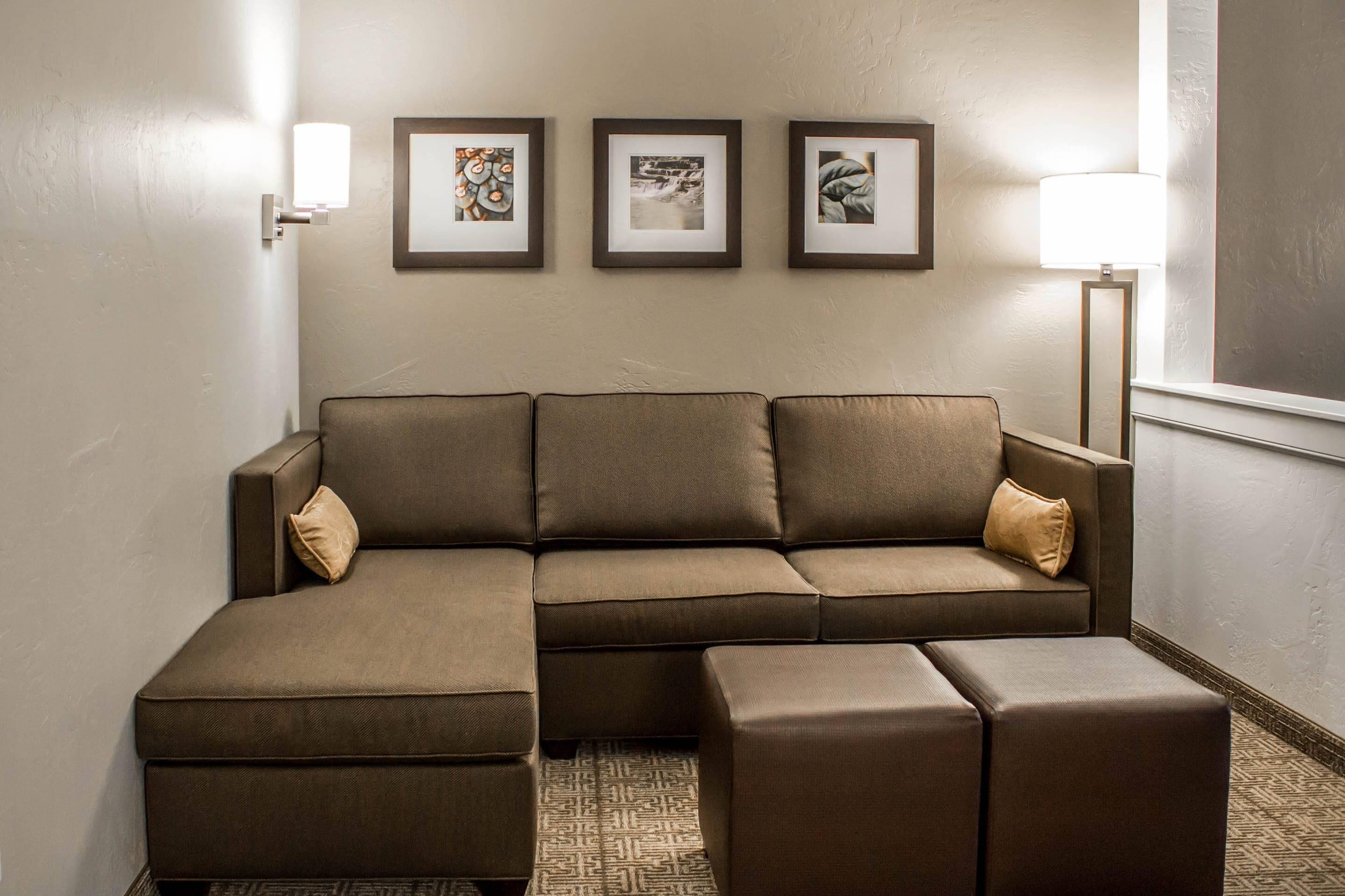 A sectional sofa with a matching ottoman, a floor lamp, and three framed pictures on the wall.
