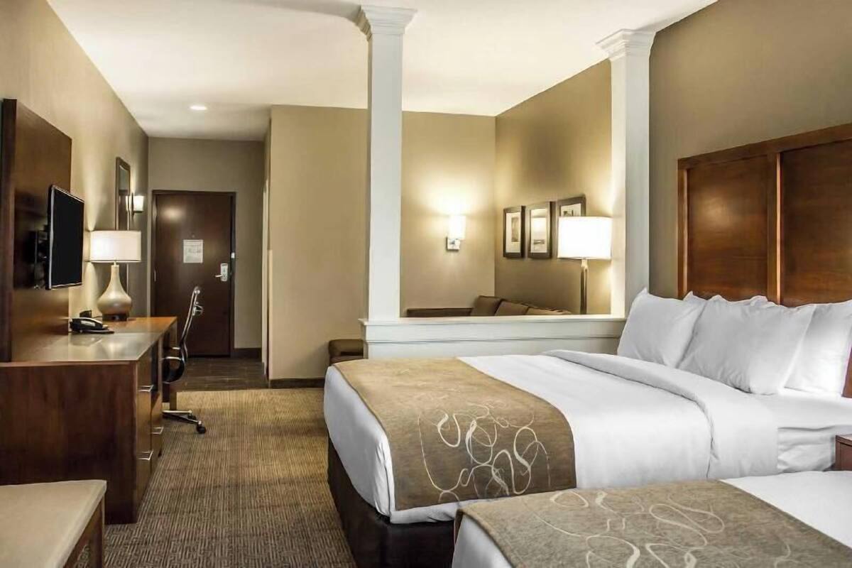 Une chambre d’hôtel avec un lit, un bureau, une chaise et un grand miroir.