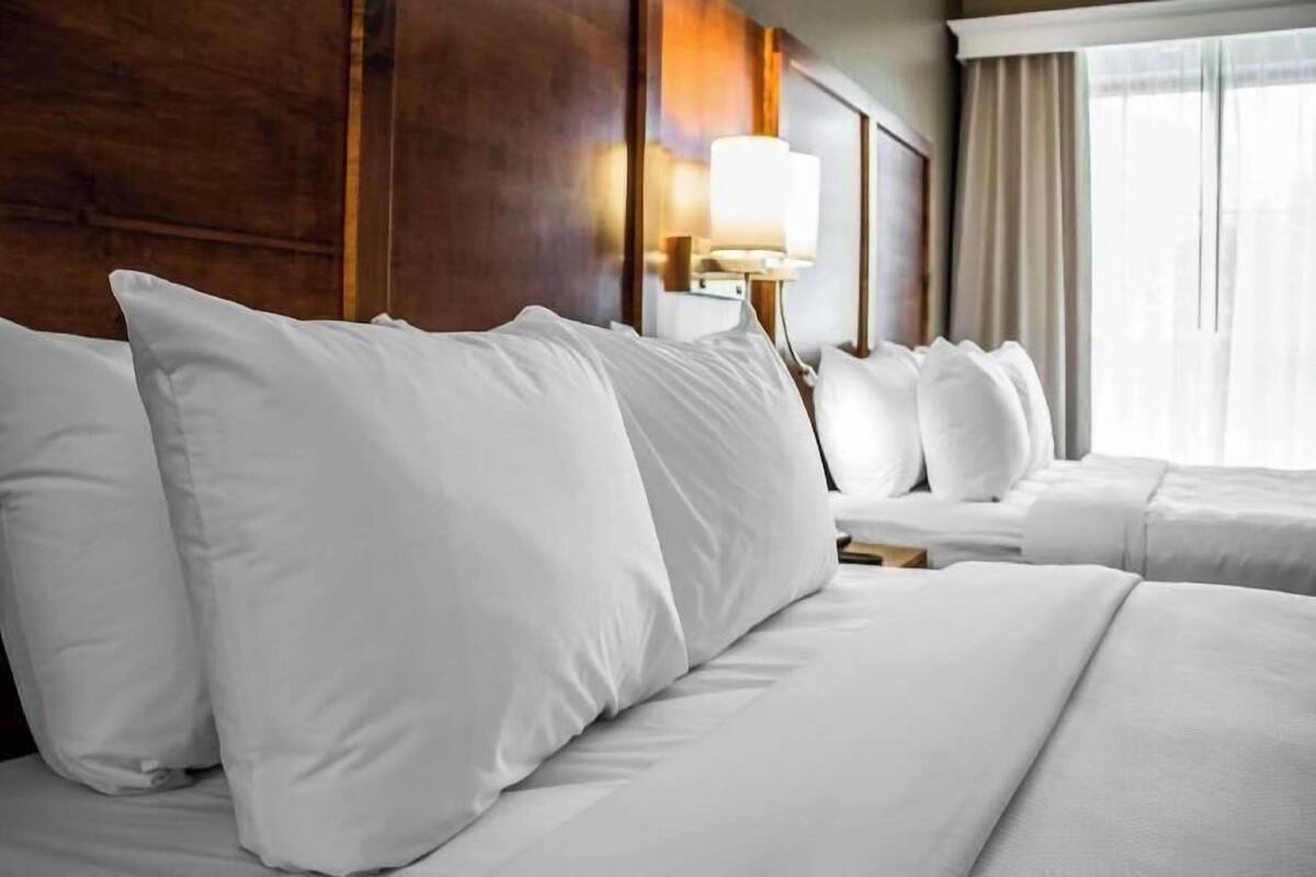 Een hotelkamer met een groot bed, een bedlamp en een raam met gordijnen.