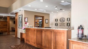 Een receptie met een houten balie, ingelijste foto's, een koffieapparaat en een bordje voor Comfort Suites Marketplace.
