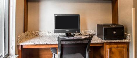 A kitchen with a granite countertop, a black computer monitor, and a printer.