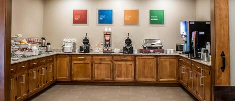 Une cuisine d’hôtel avec des meubles de rangement en bois, un coin café et un réfrigérateur.