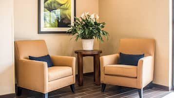 Dos sillones con cojines, una mesita de madera con una planta en maceta y un cuadro en la pared.