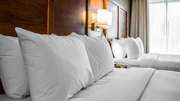 Habitación de hotel con una cama grande, una mesita de noche, una lámpara y una ventana con cortinas.