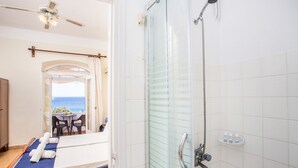 A hotel room with a bed, a shower, and a balcony with a view of the sea. - Alinda Hotel (Leros)