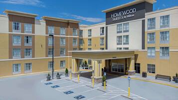 A hotel with a modern design, featuring a central entrance, multiple floors, and a sign for Homewood Suites by Hilton.