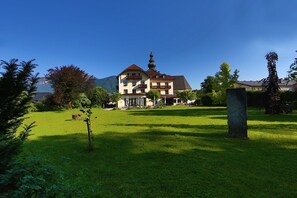 A two-story building with a red roof and a tower-like structure. - Hotel Vötterl (Grossgmain)