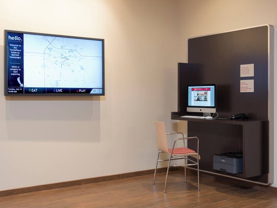 A reception area with a large digital map display, a computer monitor, a printer, and a chair.