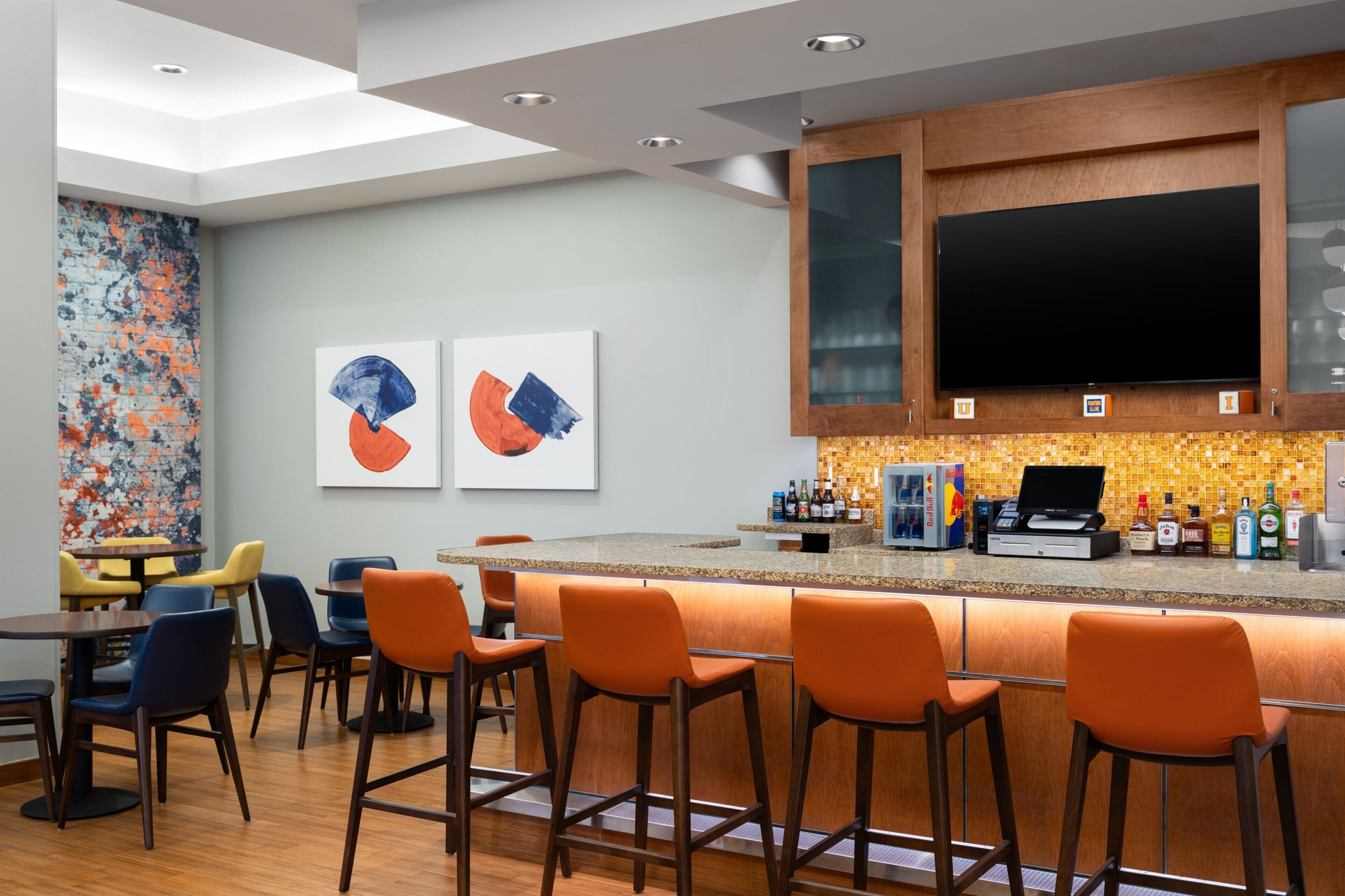 A modern bar area with a high counter, bar stools, and a seating area with tables and chairs.