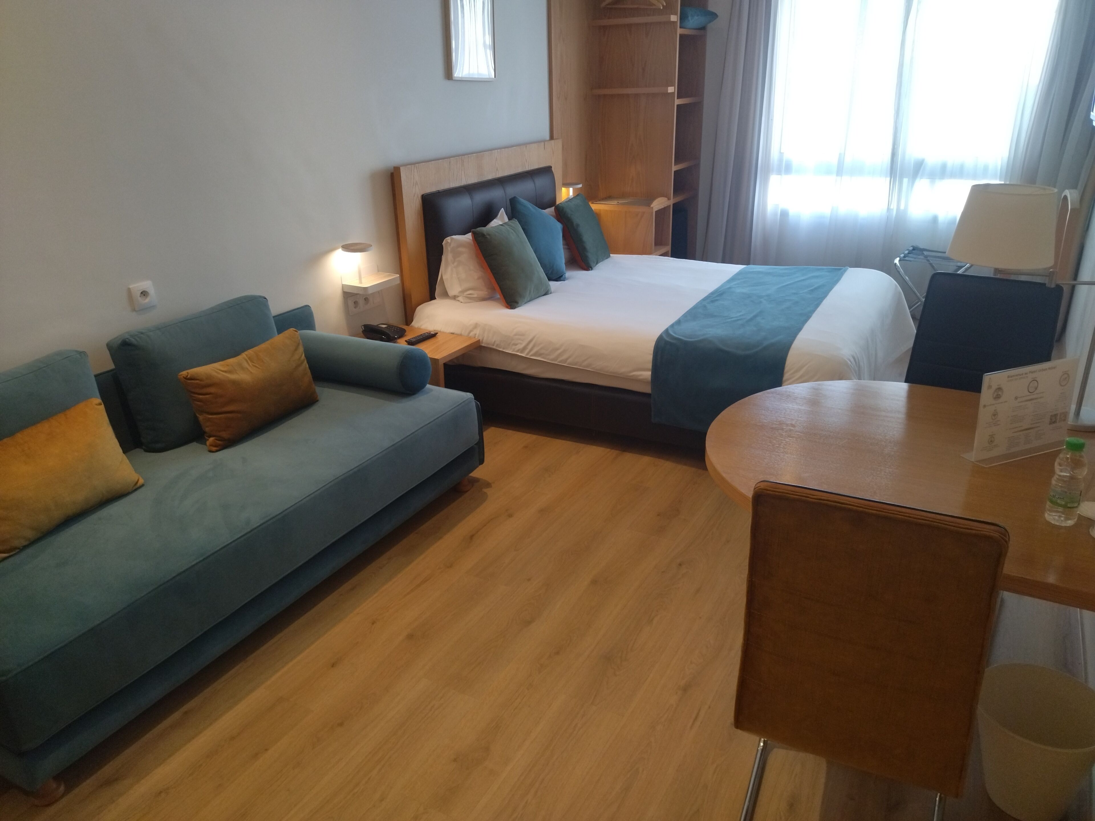 Een hotelkamer met een bed, een slaapbank, een bureau en een kledingkast.