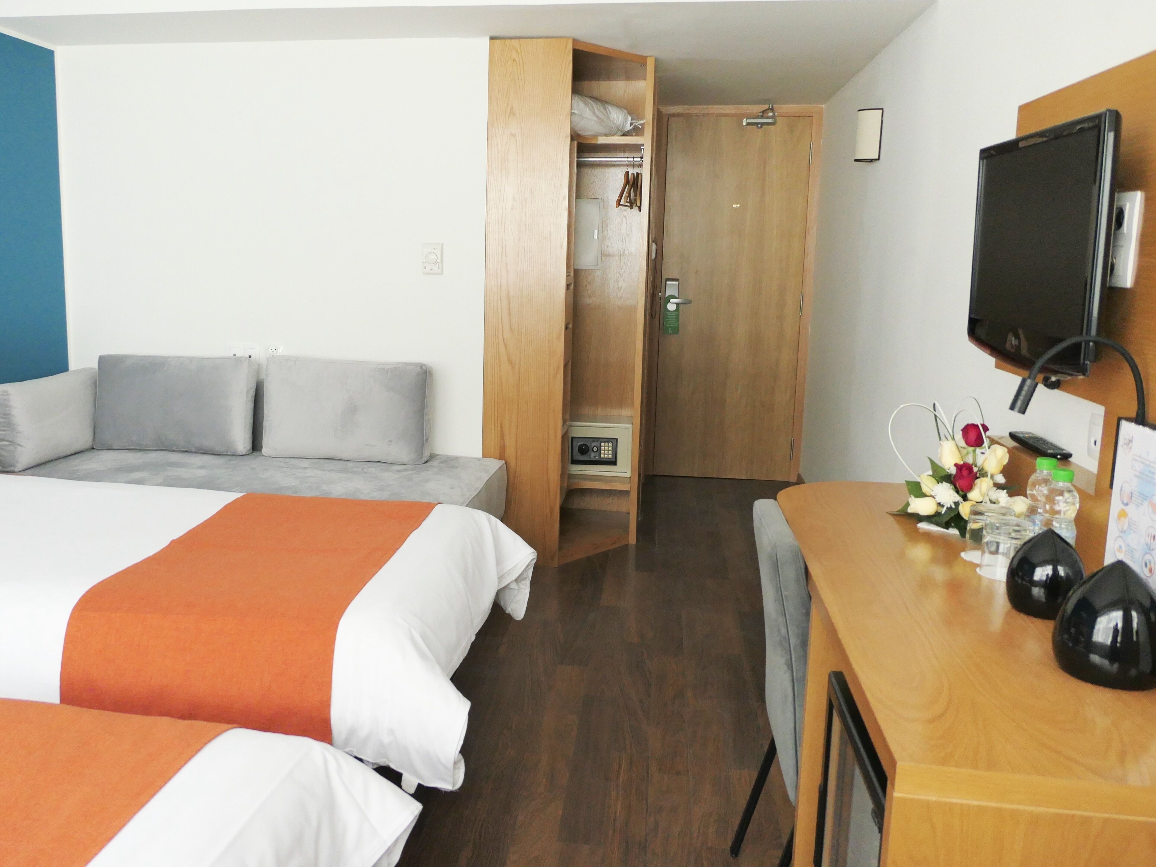 Una camera d'albergo con un letto, una scrivania con televisore e un armadio.