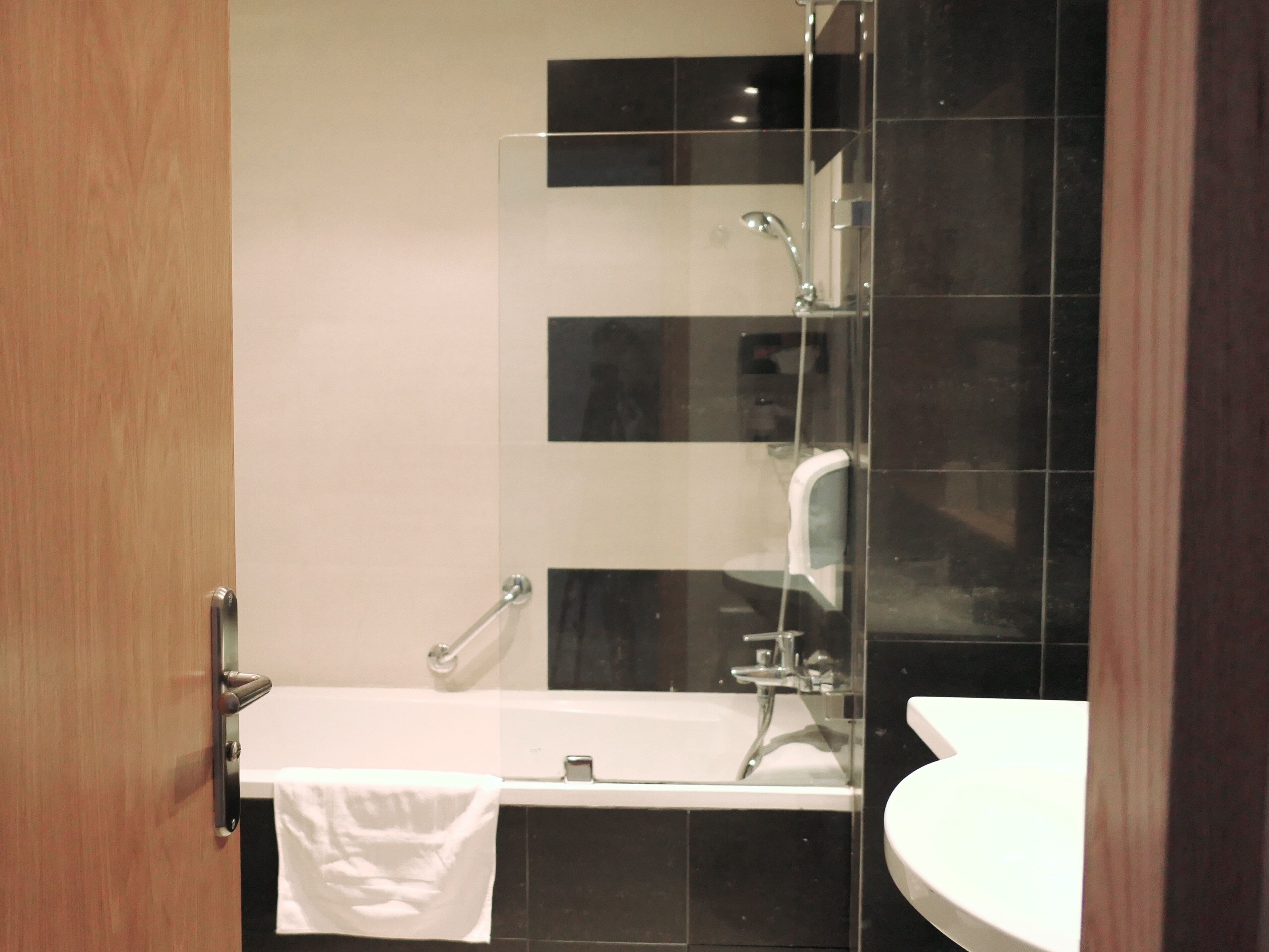 Un baño moderno con cabina de ducha de vidrio, una bañera blanca y un lavabo redondo.