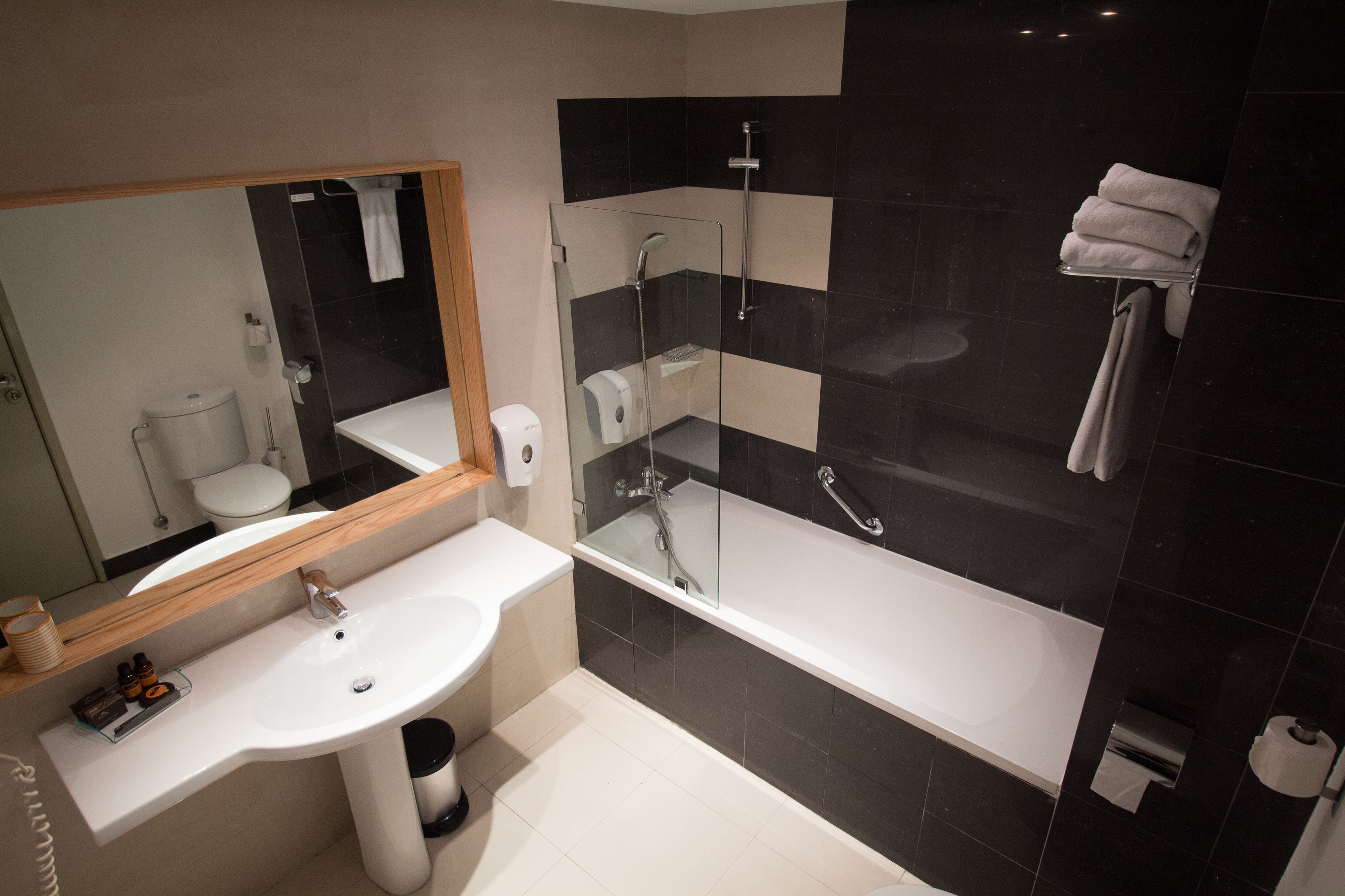 A modern bathroom with a white sink, a glass-enclosed shower, and a large bathtub.
