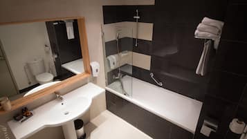 A modern bathroom with a white sink, a glass-enclosed shower, and a large bathtub.
