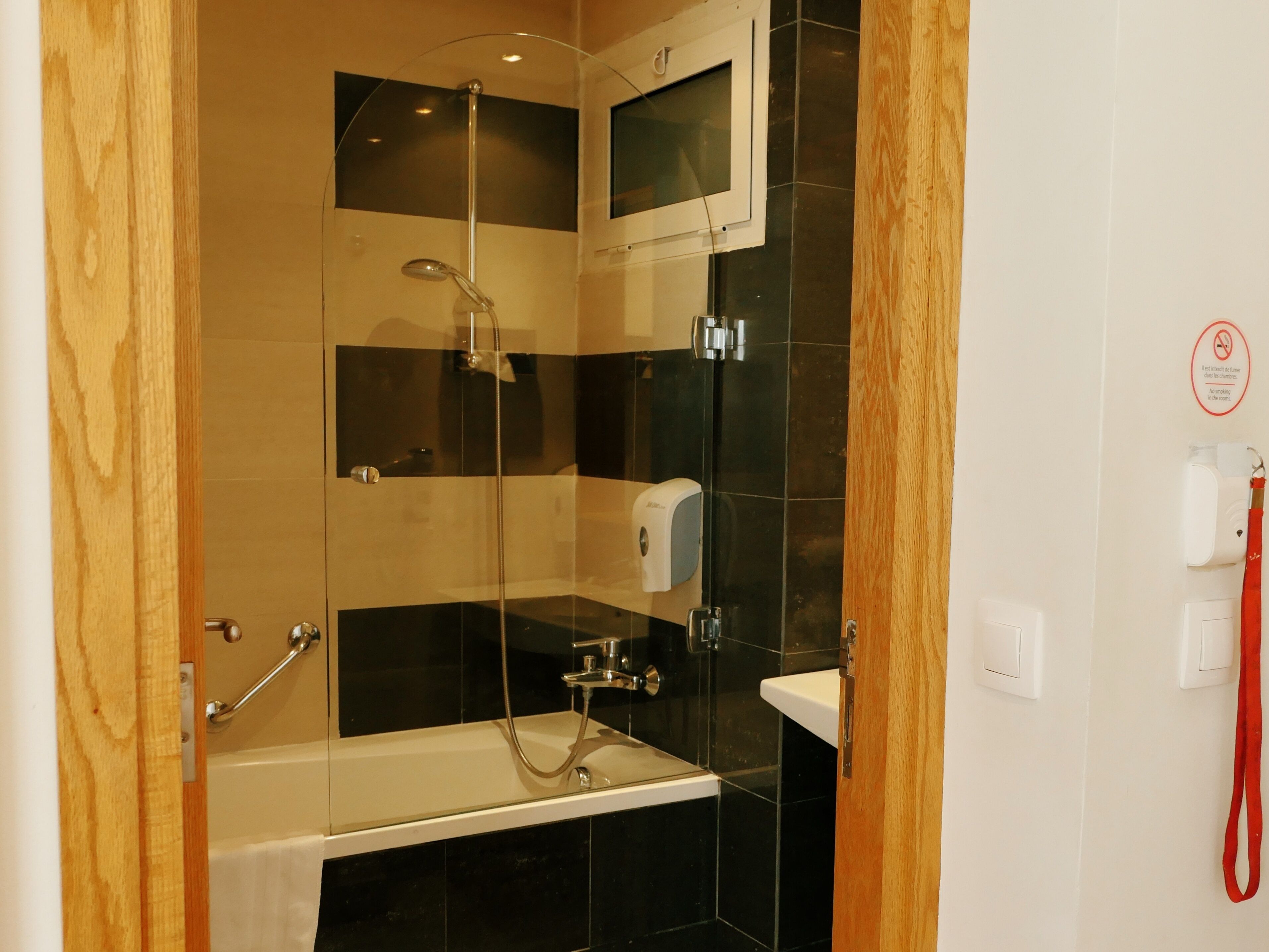 Un baño moderno con ducha de vidrio, una bañera blanca y un cabezal de ducha manual.