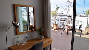 A hotel room with a wooden desk, a mirror, a potted plant, and a view of the city through large windows. - Le Pietri Urban Hotel (Rabat)