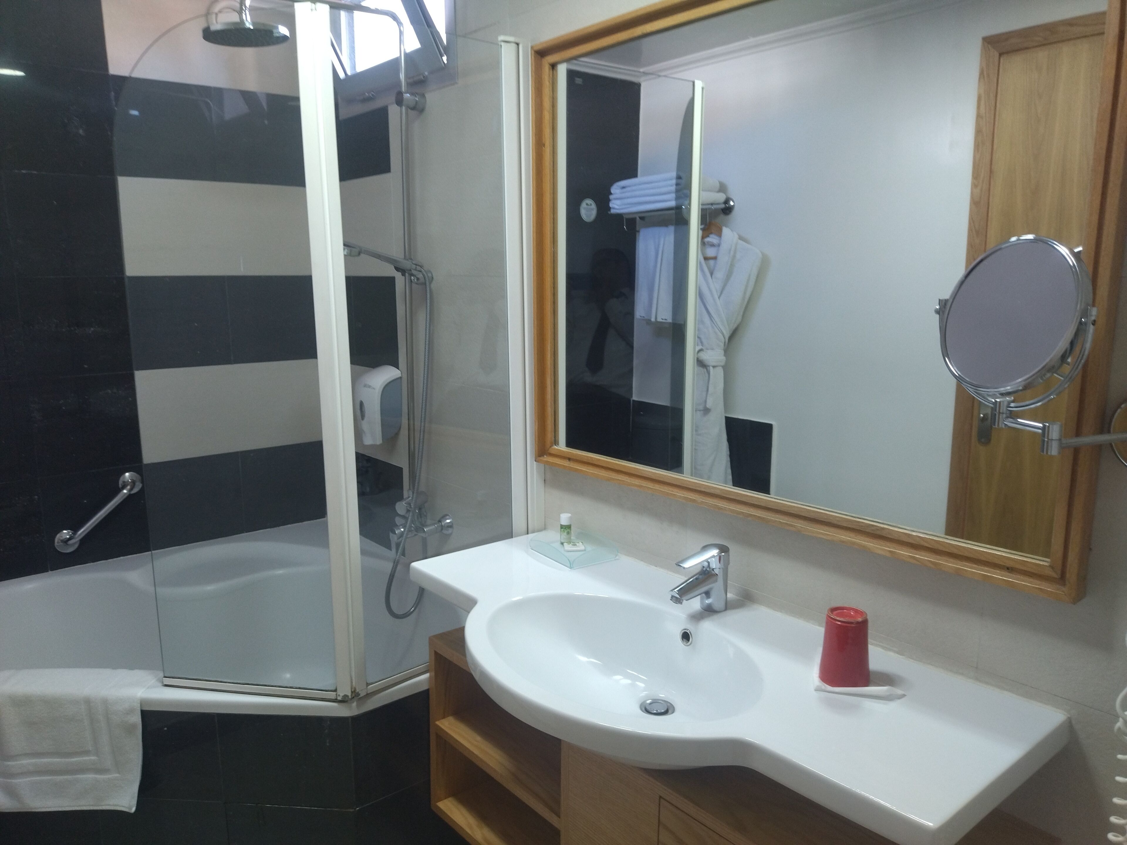 A bathroom with a shower, a sink, a mirror, and a towel rack.