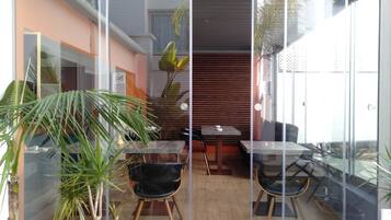 Un espace extérieur moderne, aménagé avec des cloisons en verre, un plancher en bois et des plantes en pot.
