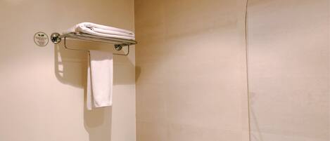 Un baño con un perchero que sostiene dos toallas, un letrero en la pared y una puerta con manija.