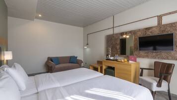 A hotel room with a large bed, a desk, a chair, a TV, and a mirror.