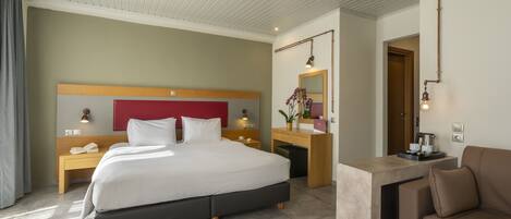 Una habitación de hotel moderna con una cama grande, un escritorio, un sofá y un baño con espejo e inodoro.