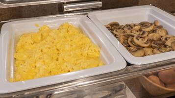 Un buffet proposant des œufs brouillés et des champignons en tranches.