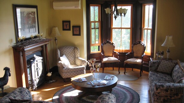 A cozy living room with patterned sofas, a fireplace, and a chandelier. - Magnetic Hill Winery (Moncton)