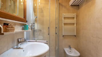 A bathroom with a sink, bidet, and glass shower enclosure.