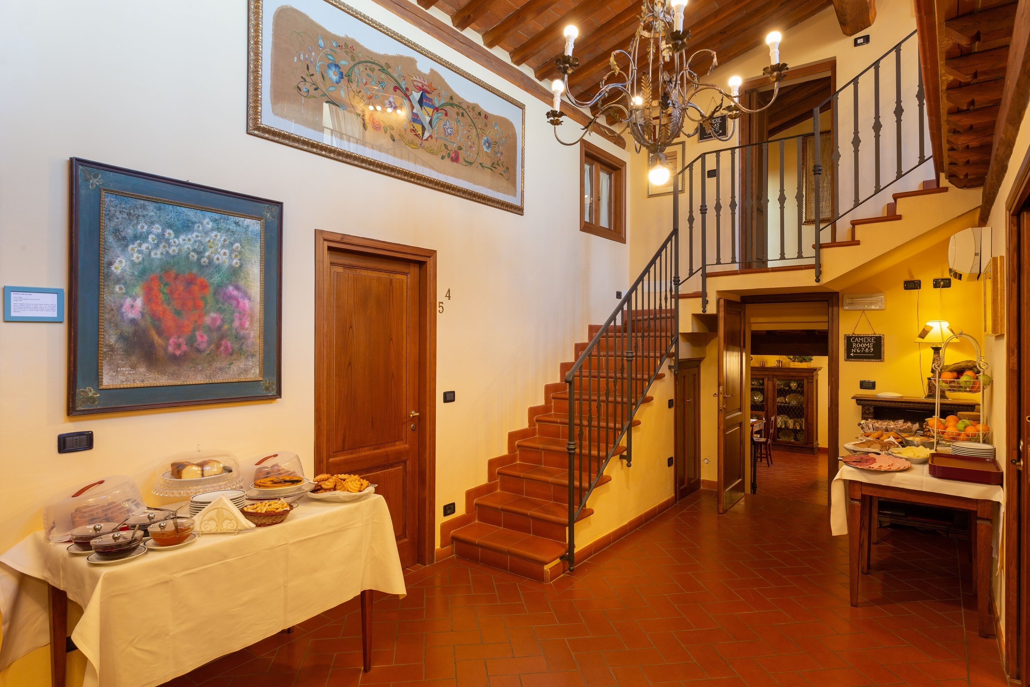 A dining area with a buffet table, a staircase, and artwork on the walls.