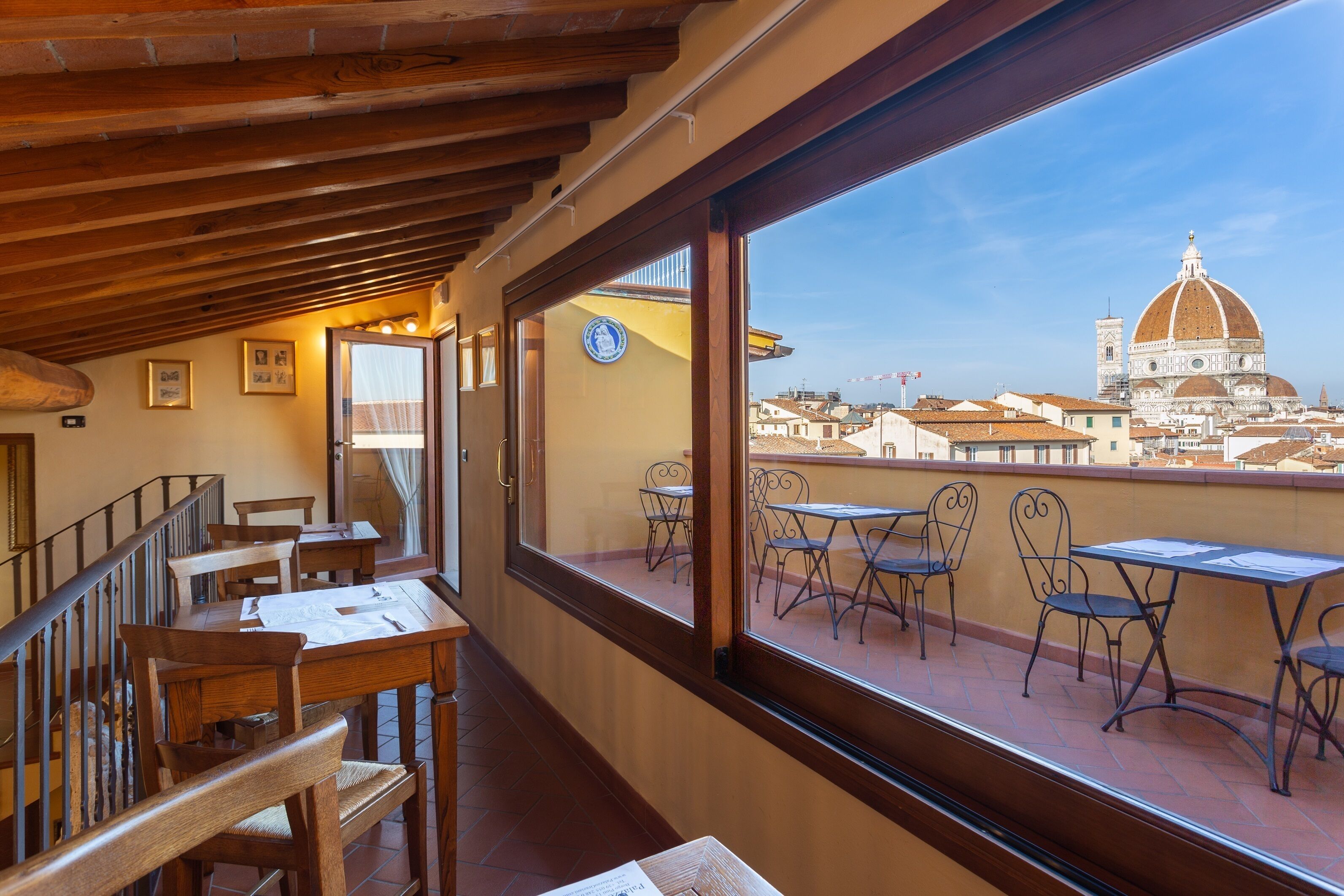 Restaurante com mobiliário de madeira e amplas janelas com vista para um horizonte urbano com uma cúpula imponente.