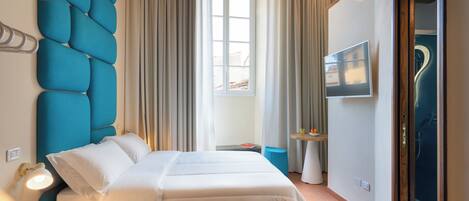 Une chambre d’hôtel avec un lit, une télévision, une salle de bain avec douche et une fenêtre avec des rideaux.
