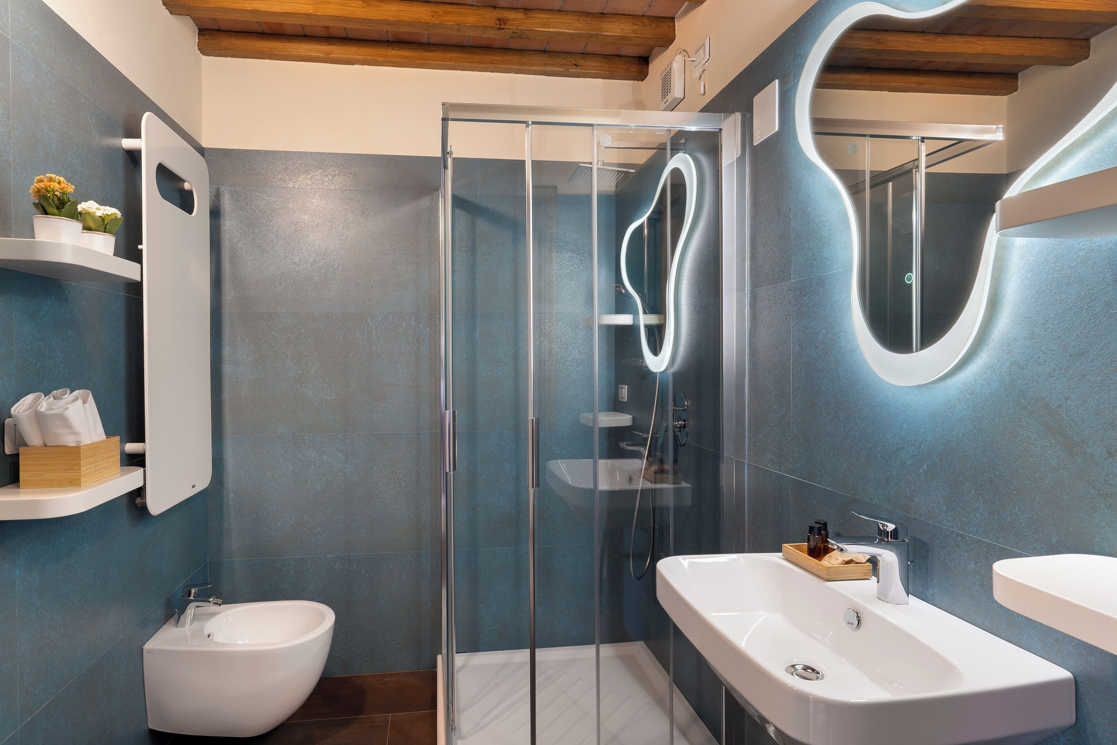 A modern bathroom with a glass-enclosed shower, a freestanding bidet, and a large sink with a mirror.