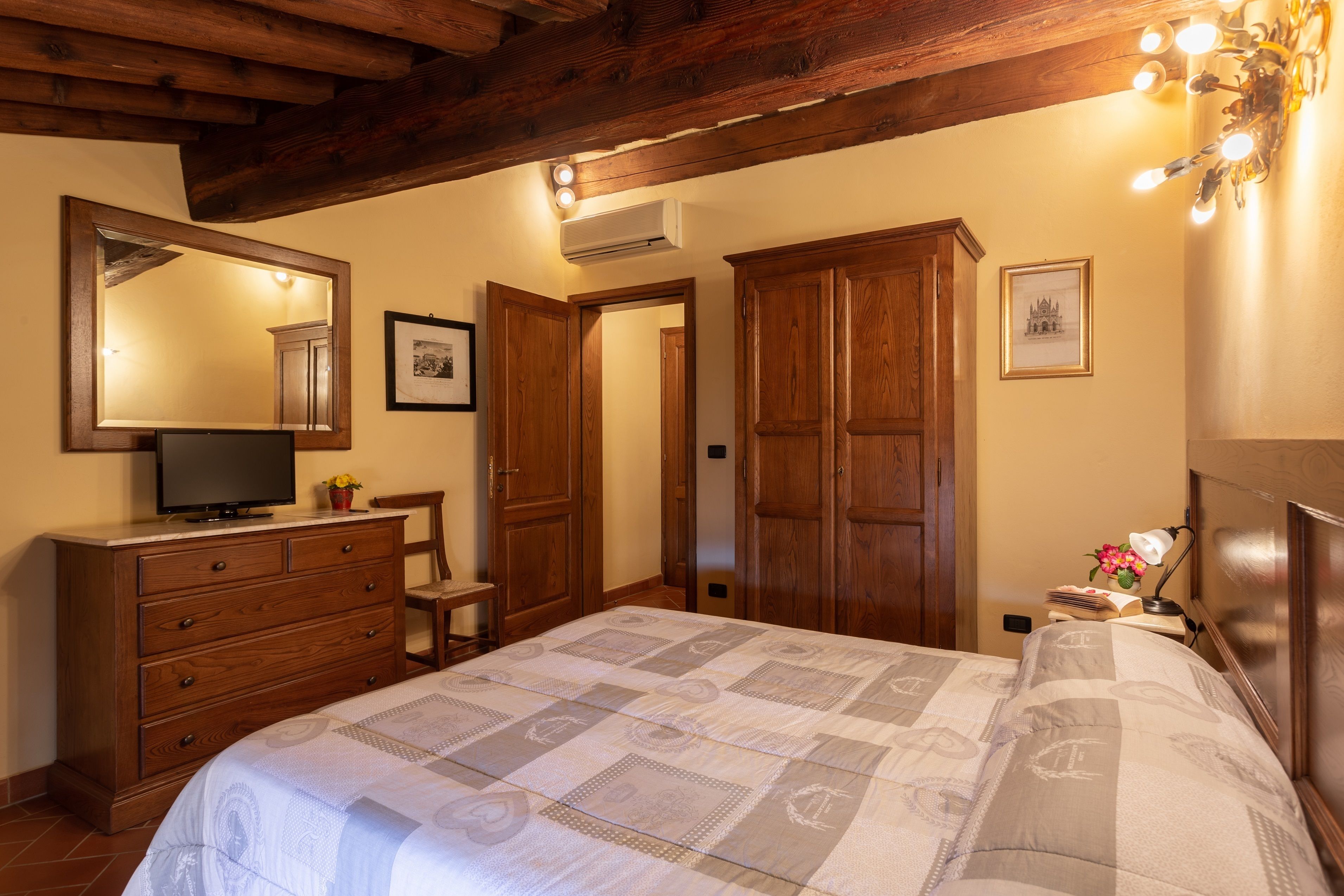 A bedroom with a bed, dresser, mirror, and wooden wardrobe.