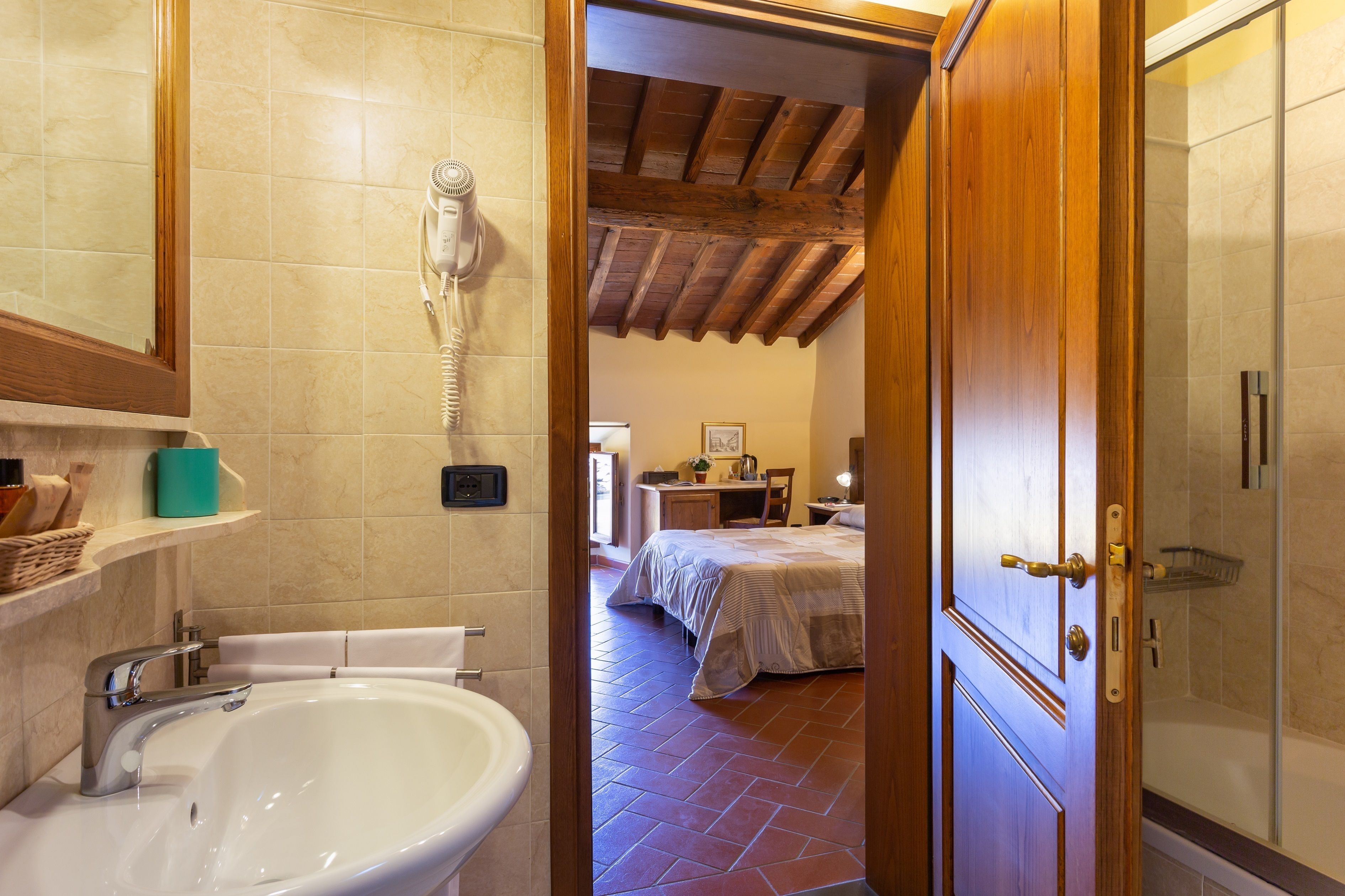 A bathroom with a sink, a hairdryer, and a shower area.