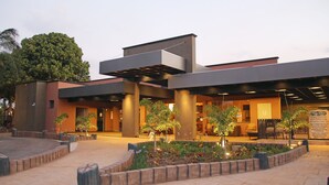 Un edificio moderno con un espacio al aire libre techado, asientos y un jardín ajardinado.