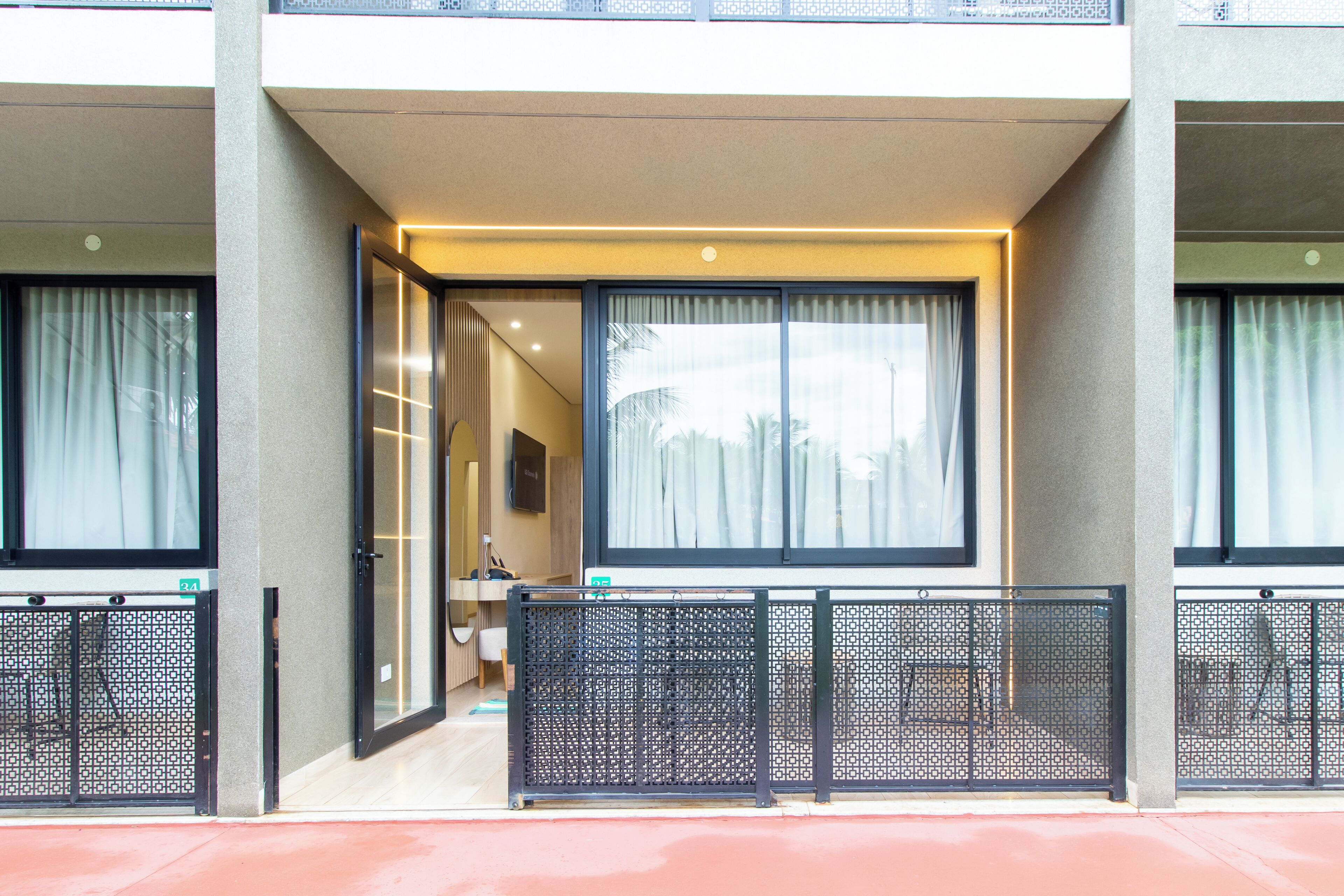 Entrada de hotel con puerta de vidrio, un mostrador de recepción y vista a la calle.