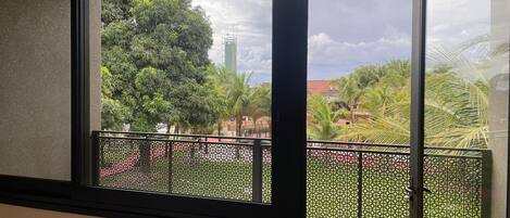 A balcony with a view of a green park and a tall building in the distance.