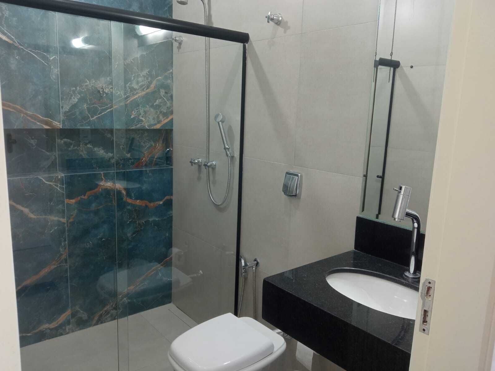 A bathroom with a glass-enclosed shower, a white toilet, and a black sink with a mirror above it.