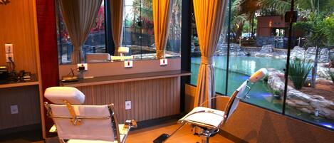 Habitación con dos sillas blancas, un espejo y ventana con vista a una piscina y zona exterior.