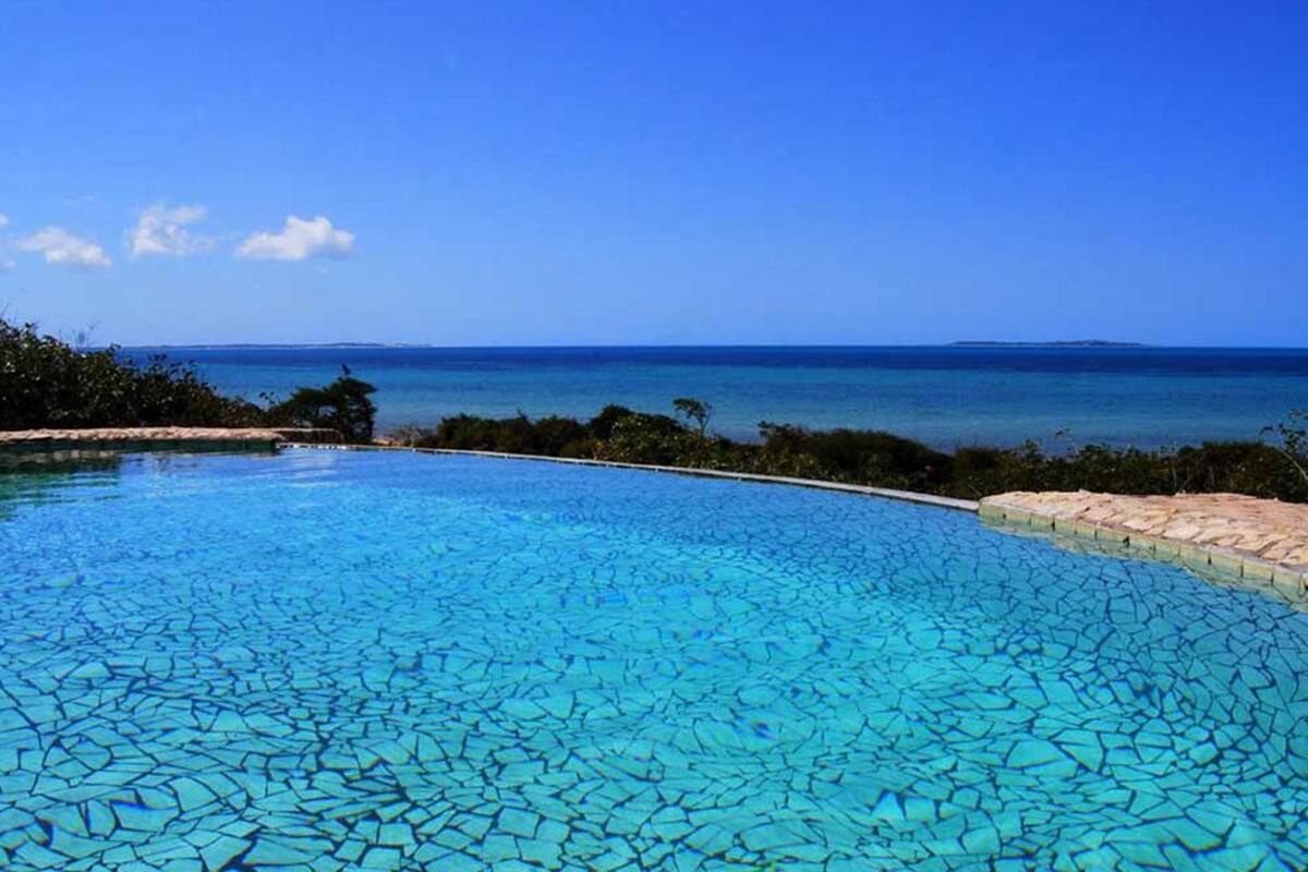 A clear blue pool with a view of the ocean and distant land.