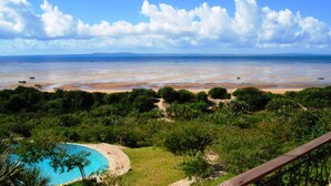 Eine Küstenlandschaft mit Schwimmbad, Strand und Meerblick.