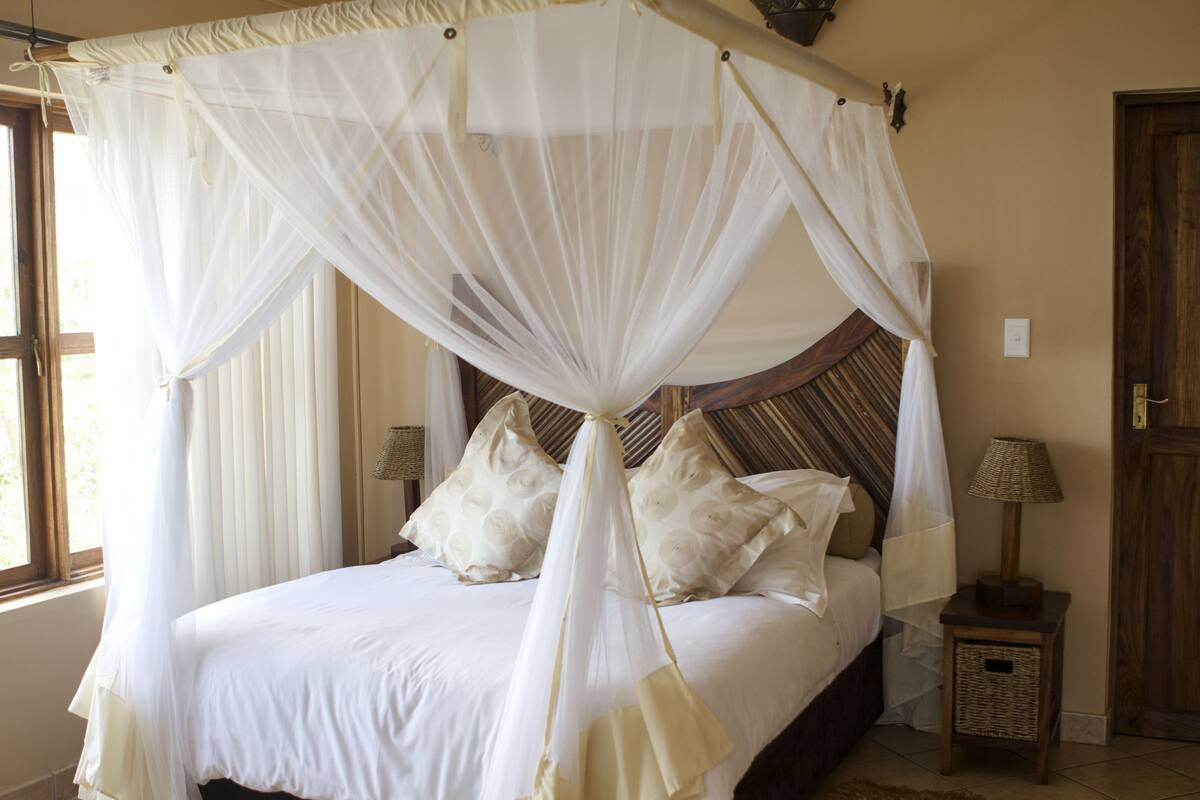 A bed with a canopy, pillows, a nightstand, and a lamp.