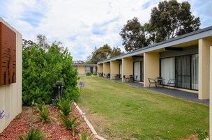 Filas de habitaciones de motel con zonas de estar al aire libre y un césped bien cuidado.