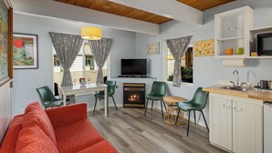 Un espacio habitable peque ño con chimenea, televisor, comedor y kitchenette.