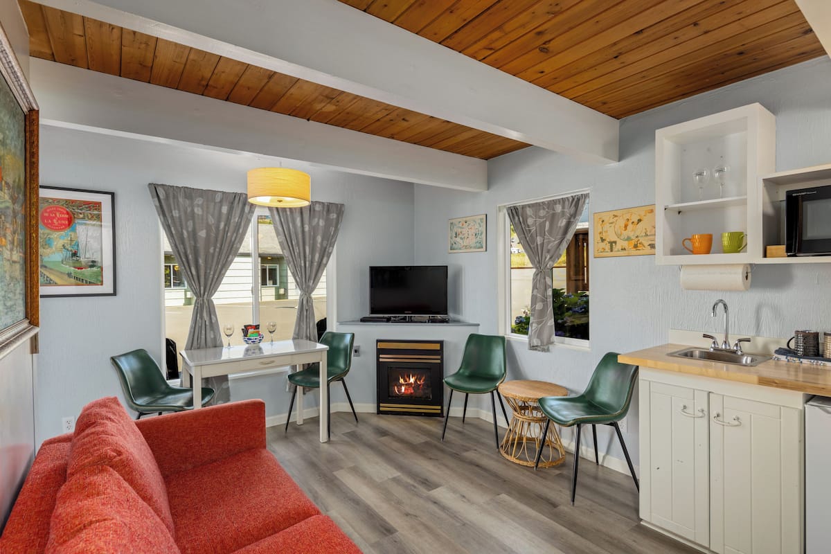 A compact living space with a fireplace, a television, a dining area, and a kitchenette.