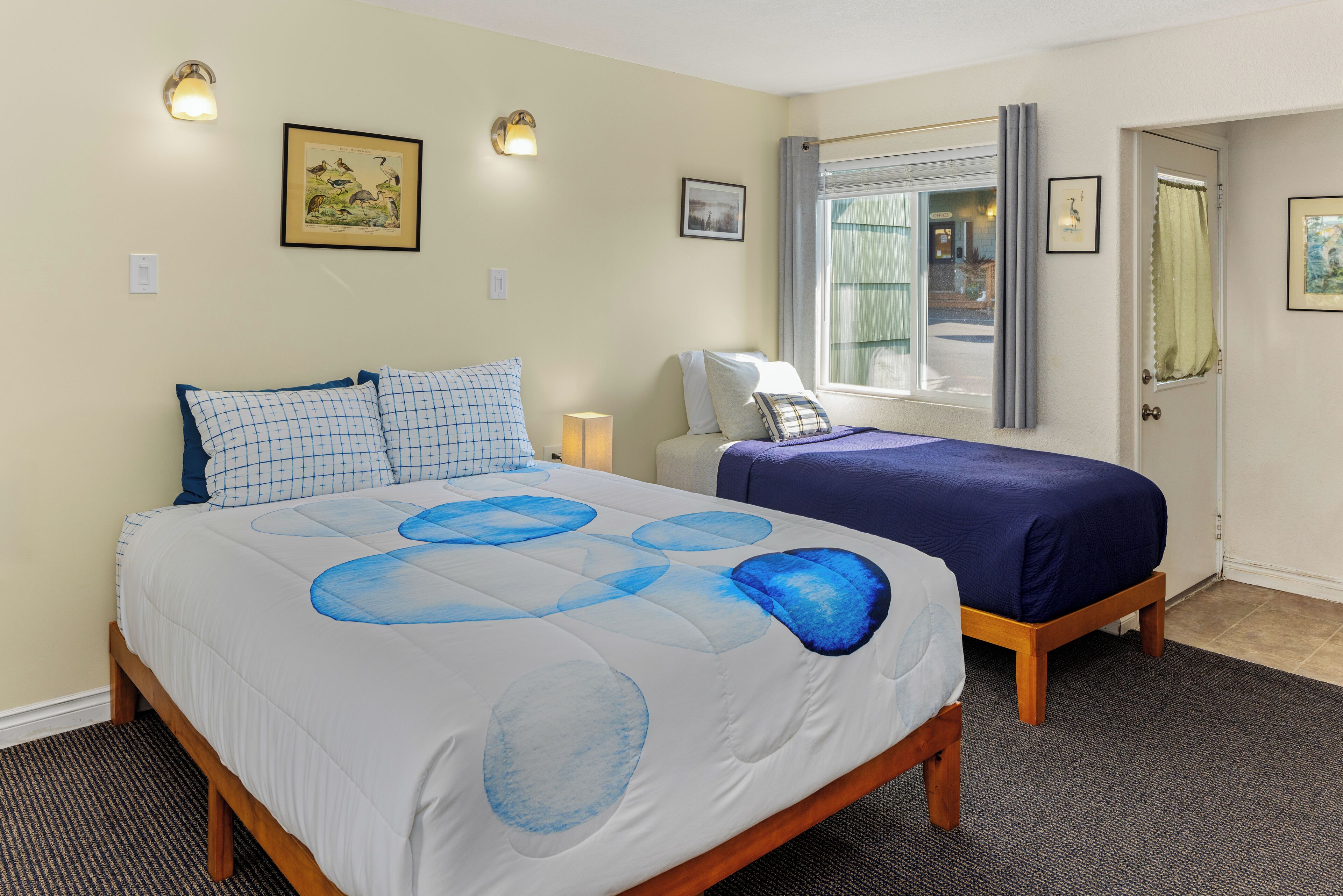 A bedroom with a bed, bedside tables, a window with curtains, and wall-mounted lights.