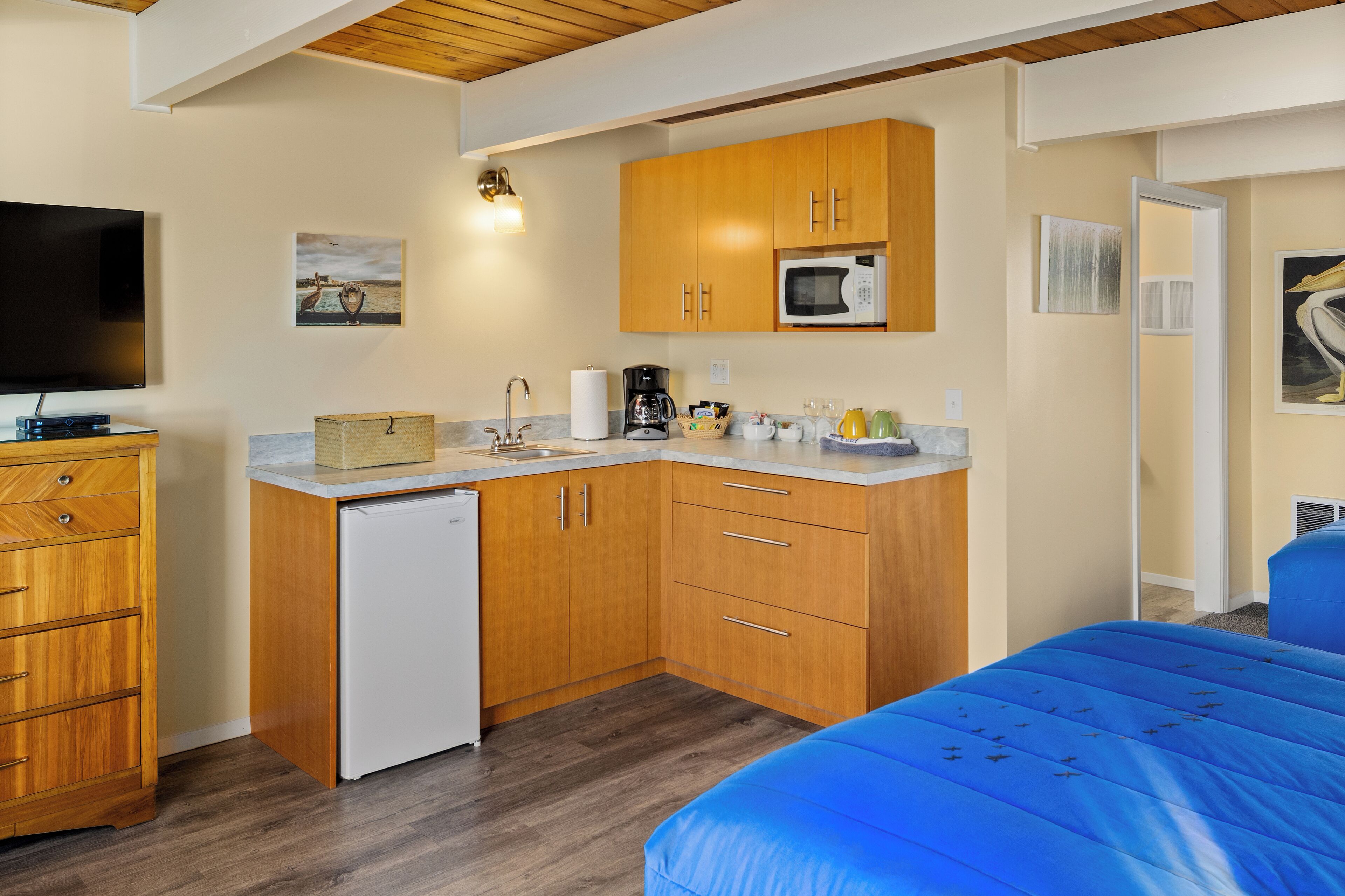 A compact kitchen with wooden cabinets, a microwave, and a small refrigerator.